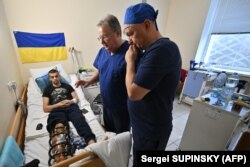 Dokter Rusia, Andrei Volna (kiri), dan Petro Nikitin (kanan), kepala departemen traumatologi dari Ukraina, memeriksa pasien di rumah sakit militer di ibu kota Ukraina, Kyiv pada 26 Januari 2024. (Foto: Sergei SUPINSKY/AFP)