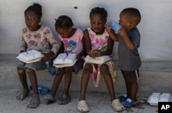 Children hold food rations at a shelter for families displaced by gang violence in the Tabarre neighborhood of Port-au-Prince on May 19, 2024. (Ramon Espinosa/AP)