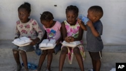 FILE - Children hold food rations at a shelter for families displaced by gang violence in the Tabarre neighborhood of Port-au-Prince, Haiti, May 19, 2024.