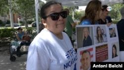 Bertha Sanles, que lleva indocumentada en Florida desde hace dos décadas, posa junto a un cartel con las fotografías de algunos legisladores estatales que aprobaron la ley SB 1718 contra la migración irregular. 