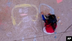 An elementary school student creates chalk art at Frye Elementary School in Chandler, Arizona, May 23, 2023.