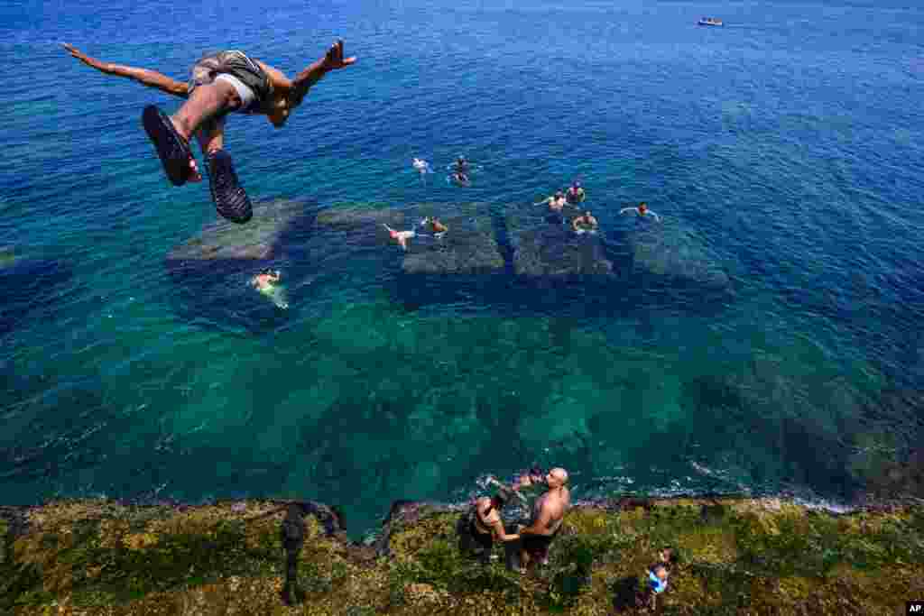 A youth jumps in the water to cool off on a sweltering hot day in the Mediterranean Sea in Beirut, Lebanon.