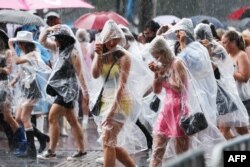 Penggemar penyanyi AS Taylor Swift, juga dikenal sebagai Swifties, berlindung dari hujan saat mereka tiba untuk menyaksikan konser Swift di Sydney pada 23 Februari 2024. (Foto: AFP)