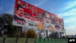 A car passes by an election billboard, ahead of Pakistan's general elections, along a road in Peshawar on Dec. 22, 2023.