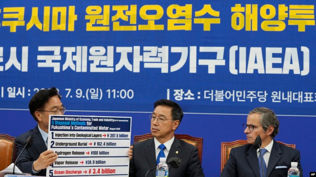 2023年7月9日，在韩国首尔举行的一次会议上，议员禹元植展示了福岛污染水的拟议处理方法，议员魏圣坤和国际原子能机构总干事拉斐尔·格罗西（右）在一旁观看。(photo:VOA)