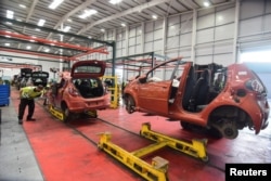 Workers at the vehicle dismantler company Charles Trent Ltd take apart a wrecked vehicle for materials and parts to reuse or recycle, on a disassembly line in Poole, Britain, June 7, 2023.