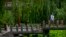 FILE - A woman walks across a bridge at a public park in Beijing, June 7, 2022. 