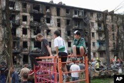 Anak-anak melihat lokasi serangan roket terbaru Rusia yang merusak gedung apartemen bertingkat di Kryvyi Rih, Ukraina, Selasa, 13 Juni 2023. (Foto: AP)