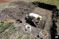 Nebraska State Archeologist Dave Williams clears away soil as workers dig for the suspected remains of children who once attended the Genoa Indian Industrial School, in Genoa, Nebraska, July 10, 2023.