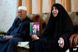 Nawal Sweidan holds a photo of her missing son in Mahmoudiya, south of Baghdad, Iraq, Tuesday, March 28, 2023.