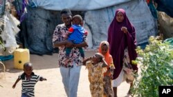 FILE - Abdikadir Omar walks to a shelter with his wife and children, who made a 12-day journey from Somalia in search of food and safety, to Dadaab refugee camp in northern Kenya, July 13, 2023. 