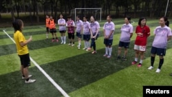 Women's soccer coach Kidd Xu, 38, talks to his team, the Netpals, before their friendly amateur game against team Halloween in Beijing, July 15, 2023. 