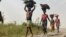 FILE - Women and children return from their farmlands after the day's work in Agatu village in Nigeria, Jan 5, 2022. The U.N. warns that the lean season in the country will heighten food security and nutrition crises there.