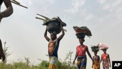 FILE - Women and children return from their farmlands after the day's work in Agatu village in Nigeria, Jan 5, 2022.