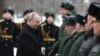 Presiden Rusia Vladimir Putin berjabat tangan di sela peringatan Hari Pembela Tanah Air di Makam Prajurit Tak Dikenal dekat Tembok Kremlin di Moskow, Rusia, 23 Februari 2024. (Foto: Sputnik/Alexander Kazakov via REUTERS)