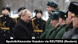 Presiden Rusia Vladimir Putin berjabat tangan di sela peringatan Hari Pembela Tanah Air di Makam Prajurit Tak Dikenal dekat Tembok Kremlin di Moskow, Rusia, 23 Februari 2024. (Foto: Sputnik/Alexander Kazakov via REUTERS)