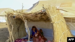 FILE—A displaced woman and her children sit in the shade of a straw hut at a camp in southern Gadaref state, for people who fled Khartoum and Jazira states in war-torn Sudan, March 20, 2024.