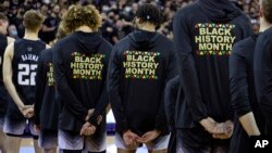 ARCHIVO - Jugadores del equipo de básquetbol universitario de Washington durante la interpretación del himno nacional con chaquetas de calentamiento con el Mes de la Historia Afroamericana impreso en la espalda, antes de jugar contra Arizona en Seattle, el 12 de febrero de 2022.