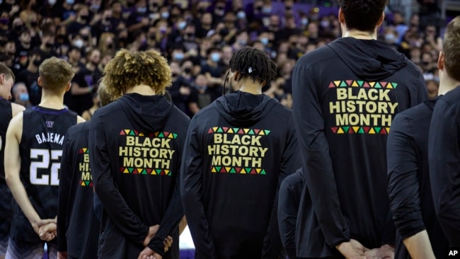 FILE - Washington players stand during the playing of the national anthem wearing warm-up jackets with Black History Month printed on the back, before playing Arizona in an NCAA college basketball game in Seattle, Feb. 12, 2022.
