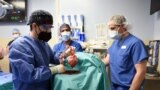 FILE — This photo released by the University of Maryland School of Medicine shows surgeons transplanting a heart from a genetically modified pig to a patient in Baltimore, Maryland, on Jan. 7, 2022. This week, the medical school performed a similar procedure on another patient.