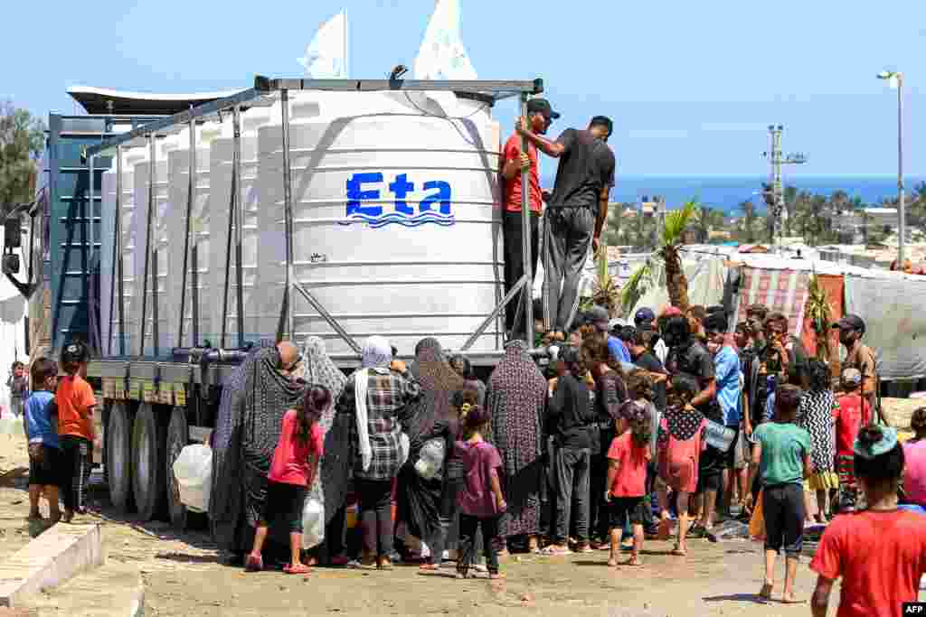 People gather to fill up their water containers from a truck loaded with water cisterns in Rafah in the southern Gaza Strip.