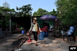 FILE - Resident Chea Srey Sar carries her belongings to be relocated by a military truck at the Angkor Wat temple area in Siem Reap province on January 16, 2023.