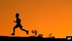 La silueta de un niño se recorta contra el cielo al atardecer mientras corre a lo largo de una cresta en Papago Park, el viernes 1 de abril de 2022, en Phoenix. (Foto AP/Charlie Riedel)