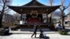 FILE - A woman pushes her child past a hall displaying 'hina' dolls at a Shinto shrine in Tokyo, March 3, 2023.