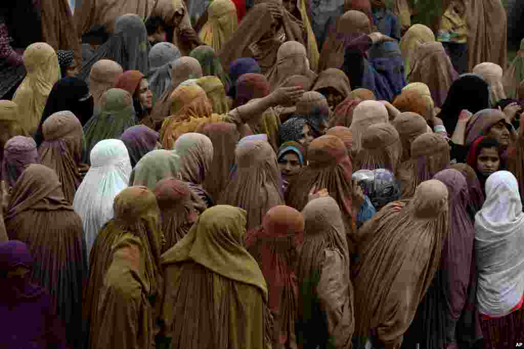Women gather and wait their turn to get a free sack of wheat flour at a pickup point, in Peshawar, Pakistan.