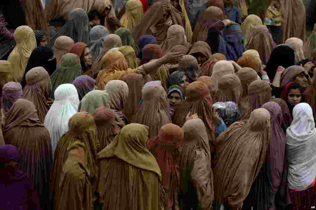 Kaum perempuan berkumpul dan menunggu giliran untuk menerima sekarung tepung terigu gratis di pusat distribusi bantuan makanan di kota Peshawar, Pakistan.