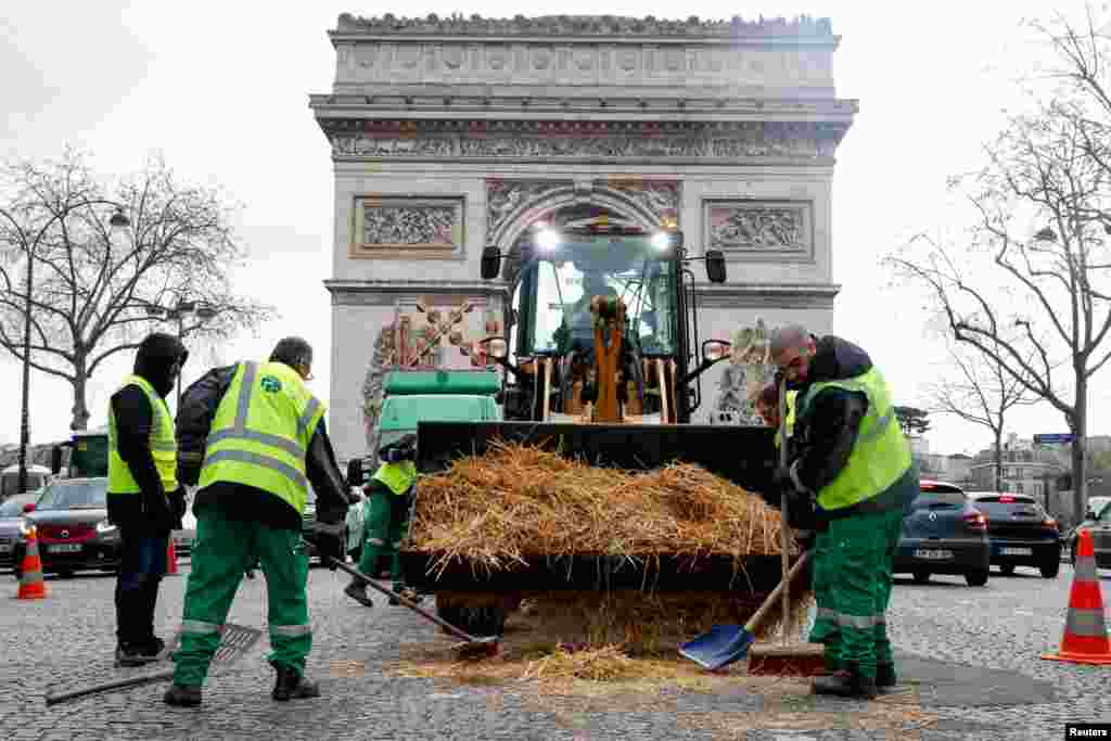 Општинските работници чистат слама за време на протестот на земјоделците, во Париз, Франција.