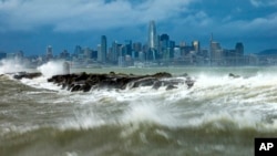 Waves crash over a breakwater in Alameda, California, with the San Francisco skyline in the background, Feb. 4, 2024. High winds and heavy rainfall are impacting the region.