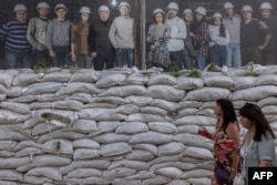 People walk past sandbags protecting a theater on Andriivskyi Descent in the Podil neighborhood in Kyiv on July 25, 2023.