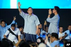 Calon presiden Prabowo Subianto, kiri, dan pasangannya Gibran Rakabuming Raka, menyapa para pendukungnya saat berkumpul di Jakarta, 14 Februari 2024. (Foto: AP)