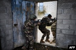 Tentara Ukraina berjalan melewati sebuah gedung selama latihan dengan tentara Prancis di kamp militer Prancis di Prancis, November 2023. (OLIVIER CHASSIGNOLE / AFP)