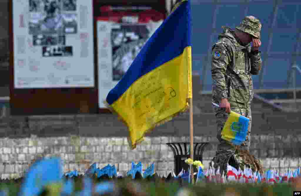 A serviceman mourns next to a Ukrainian flag at a makeshift memorial for fallen soldiers at Independence Square in Kyiv, amid the Russian invasion of Ukraine.