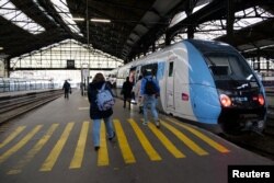 Penumpang kereta api berjalan di peron stasiun kereta api Saint-Lazare pada hari kesembilan pemogokan nasional dan protes di Paris, Prancis, 23 Maret 2023. (REUTERS/Lucien Libert)