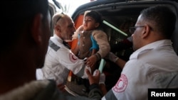 Members of the Palestine Red Crescent Society assist a Palestinian child as wounded Palestinians are rushed into Nasser hospital following Israeli strikes, in Khan Younis, in the southern Gaza Strip, Dec. 4, 2023. 