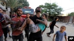 FILE - Palestinians carry a wounded girl after being rescued from under the rubble of buildings that were destroyed by Israeli airstrikes in Jabaliya refugee camp, northern Gaza Strip, Nov. 1, 2023.