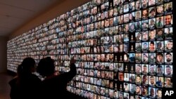 ARCHIVO - Visitantes miran fotografías de israelíes que murieron durante el ataque de Hamas el 7 de octubre y de aquellos que murieron durante la guerra en la Franja de Gaza, exhibidas en una pantalla gigante en la Biblioteca Nacional en Jerusalén, el 28 de enero de 2024.