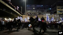 Israeli police officers on horseback disperse demonstrators blocking a highway during a protest against plans to overhaul the judicial system in Tel Aviv, Israel, March 25, 2023.