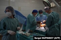 Dokter Rusia, Andrei Volna (tengah) saat melakukan operasi terhadap tentara Ukraina berusia 35 tahun, yang kehilangan sebagian kakinya selama pengepungan Rusia terhadap Mariupol, 27 Januari. 2024. (Foto: Sergei SUPINSKY/AFP)