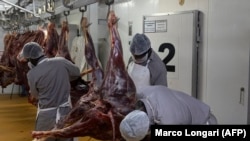 Tukang daging memotong daging buruan saat bangkai digantung di rumah potong hewan di Bela Bela, pada 22 April 2024. (Foto: AFP/Marco Longari)