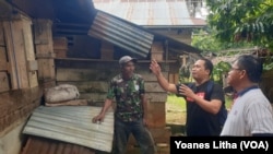 Kepala Dusun Tamanjeka, Muhammad Sambara (pakai topi) memperlihatkan kotak sarang lebah trigona yang diletakkan menempel di dinding rumah, Minggu, 14 Januari 2024. (Foto : VOA/Yoanes Litha)