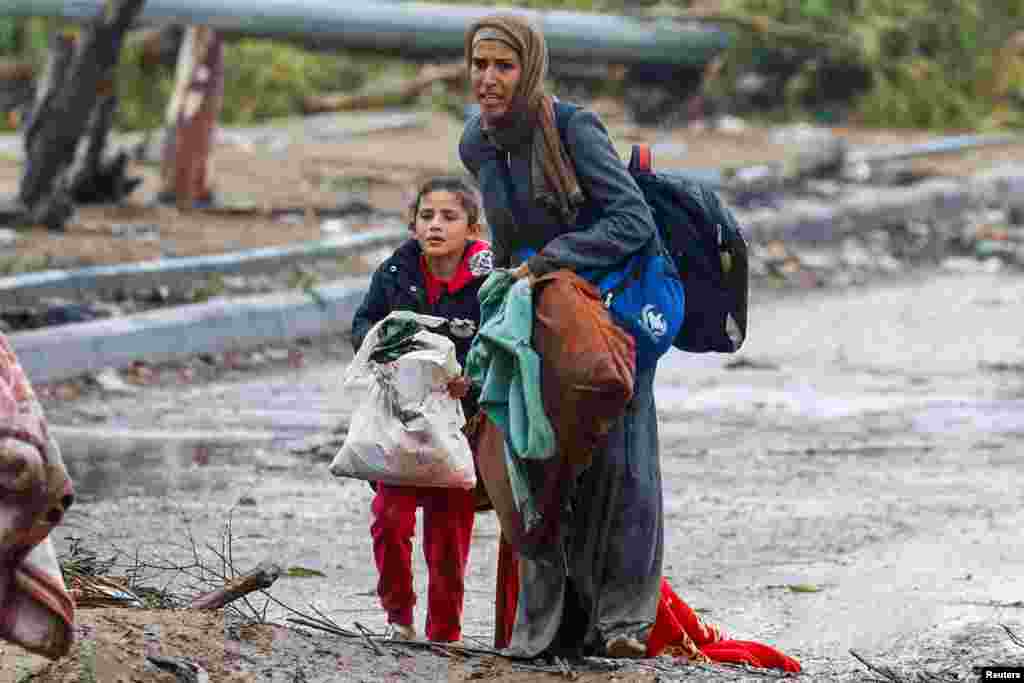 A barefooted Palestinian woman fleeing north Gaza with her daughter moves southward&nbsp;during rainfall amid a temporary truce between Israel and Hamas, near Gaza City.