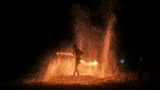 A fire dancer performs during a show for tourists on Batu Ferringhi Beach on Penang Island, Malaysia, July 11, 2024. 