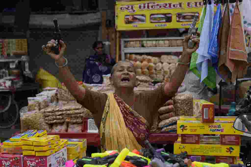 Улична продавачка која продава пиштоли-играчки со петарди се обидува да привлече клиенти во Ахмедабад, Индија.