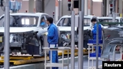 FILE - Employees work on assembly line during a construction completion event of SAIC Volkswagen MEB electric vehicle plant in Shanghai, China, Nov. 8, 2019.