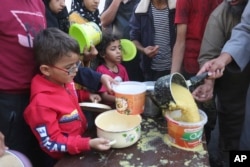 Palestinians line up for food during the ongoing Israeli bombardment of the Gaza Strip in Rafah, Nov. 13, 2023.