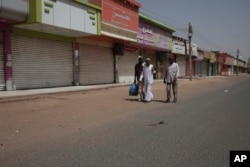 People walk past shuttered shops in Khartoum, Sudan, April 17, 2023.